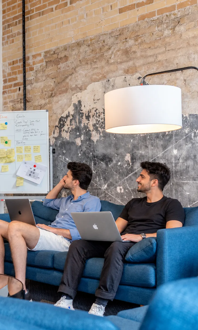 Two people on a sofa with laptops, planning a project